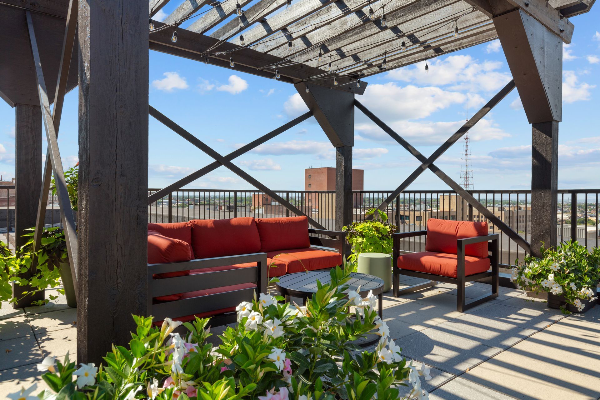 Rooftop patio with red seating, pergola shade, and city skyline view