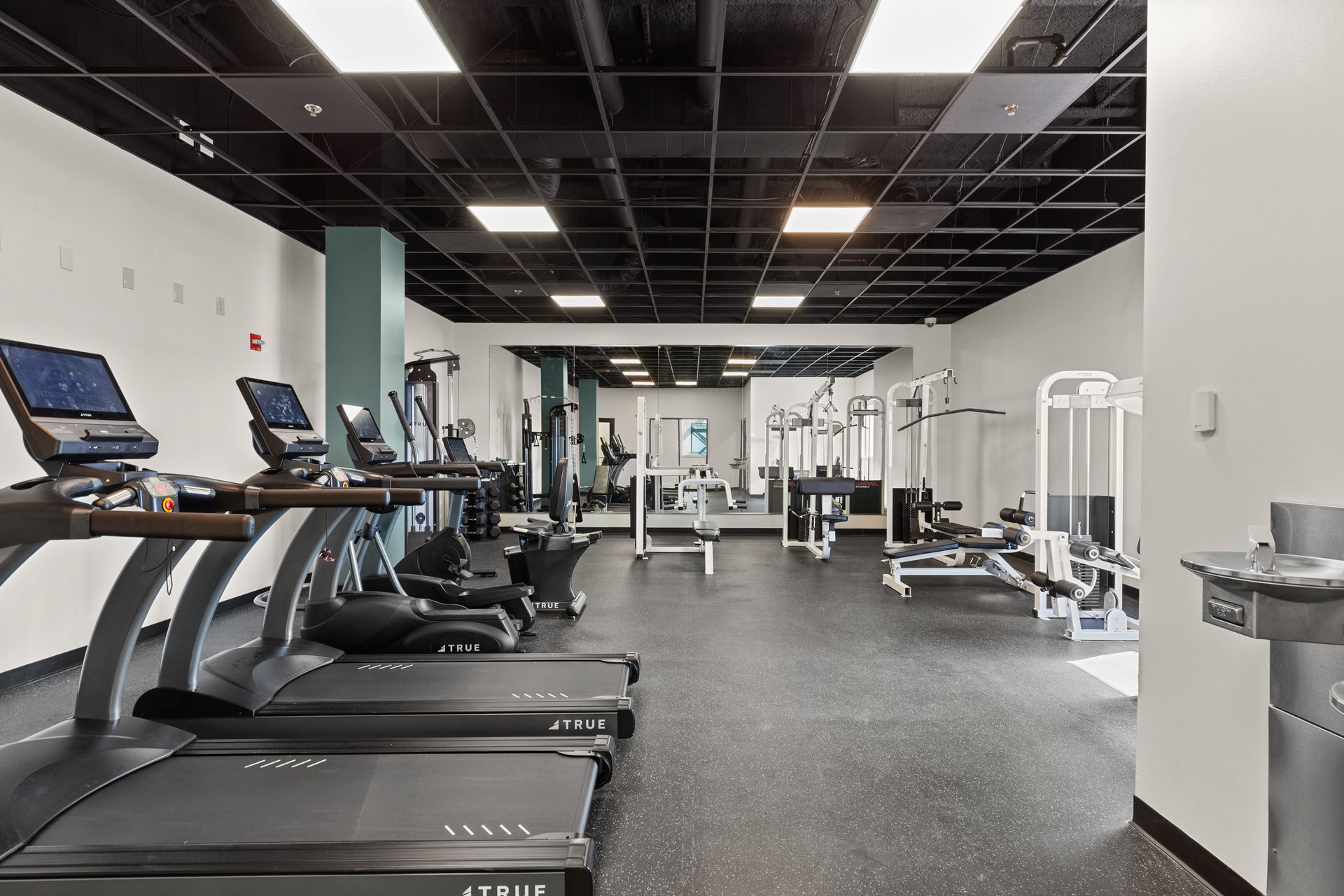 Modern gym with treadmills, weight machines, and black-and-white interior lighting