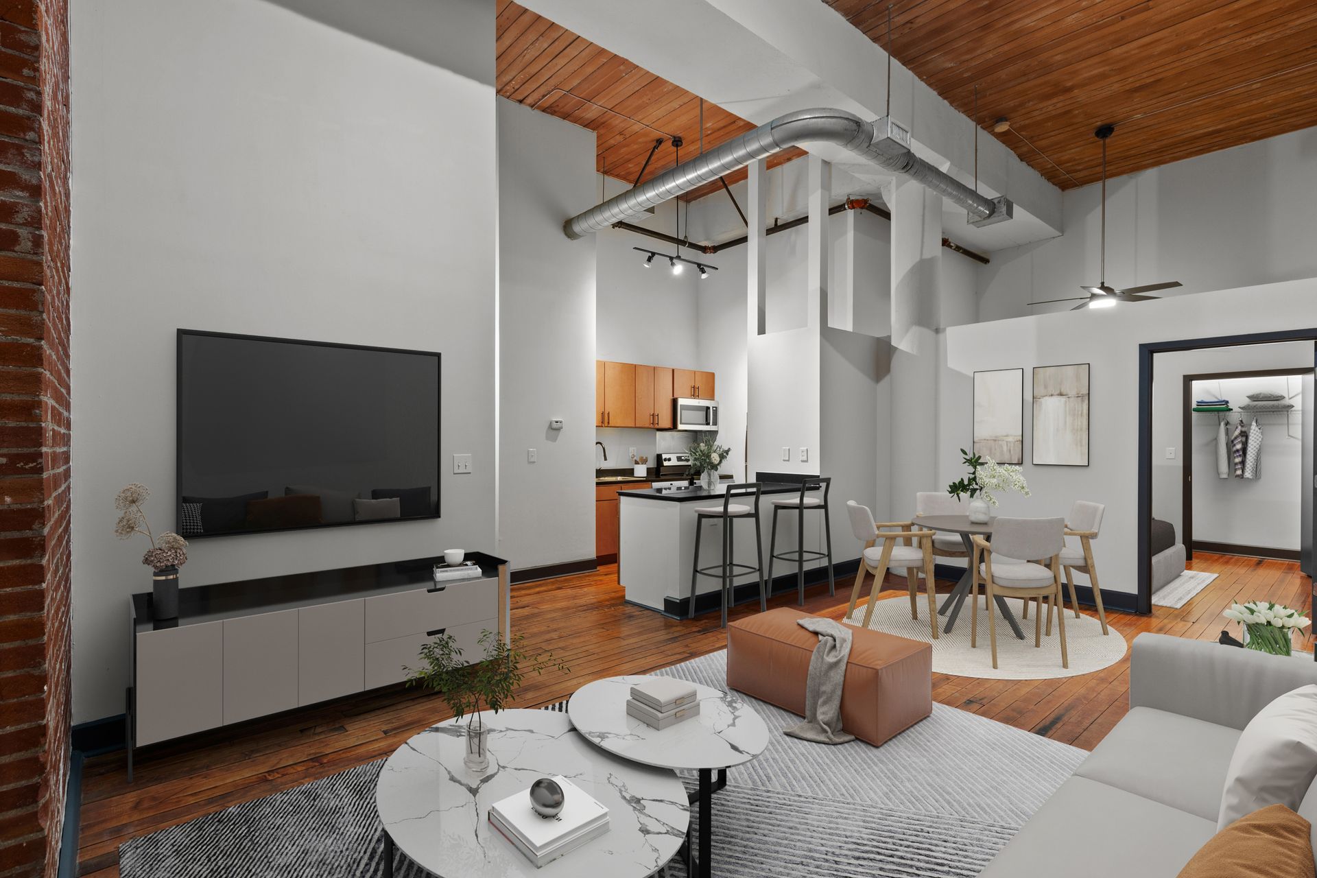 Modern loft living room with TV, white sofa, dining area, and exposed wood ceiling