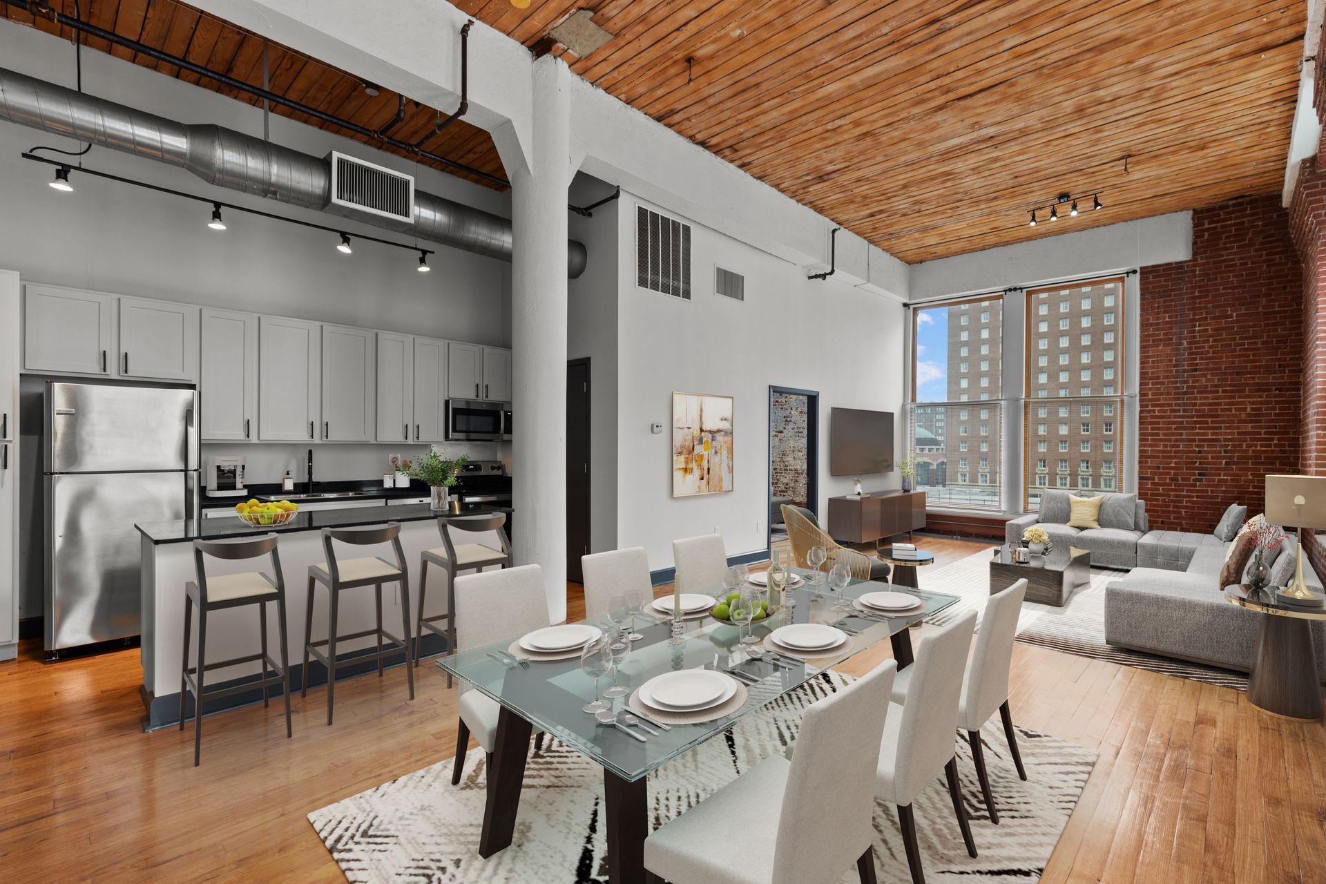 Loft apartment dining area with kitchen, exposed brick, high wood ceiling, and city-view windows