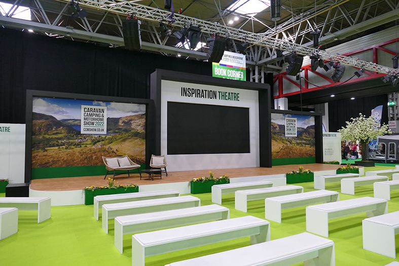 A large room with a lot of benches and a large screen.
