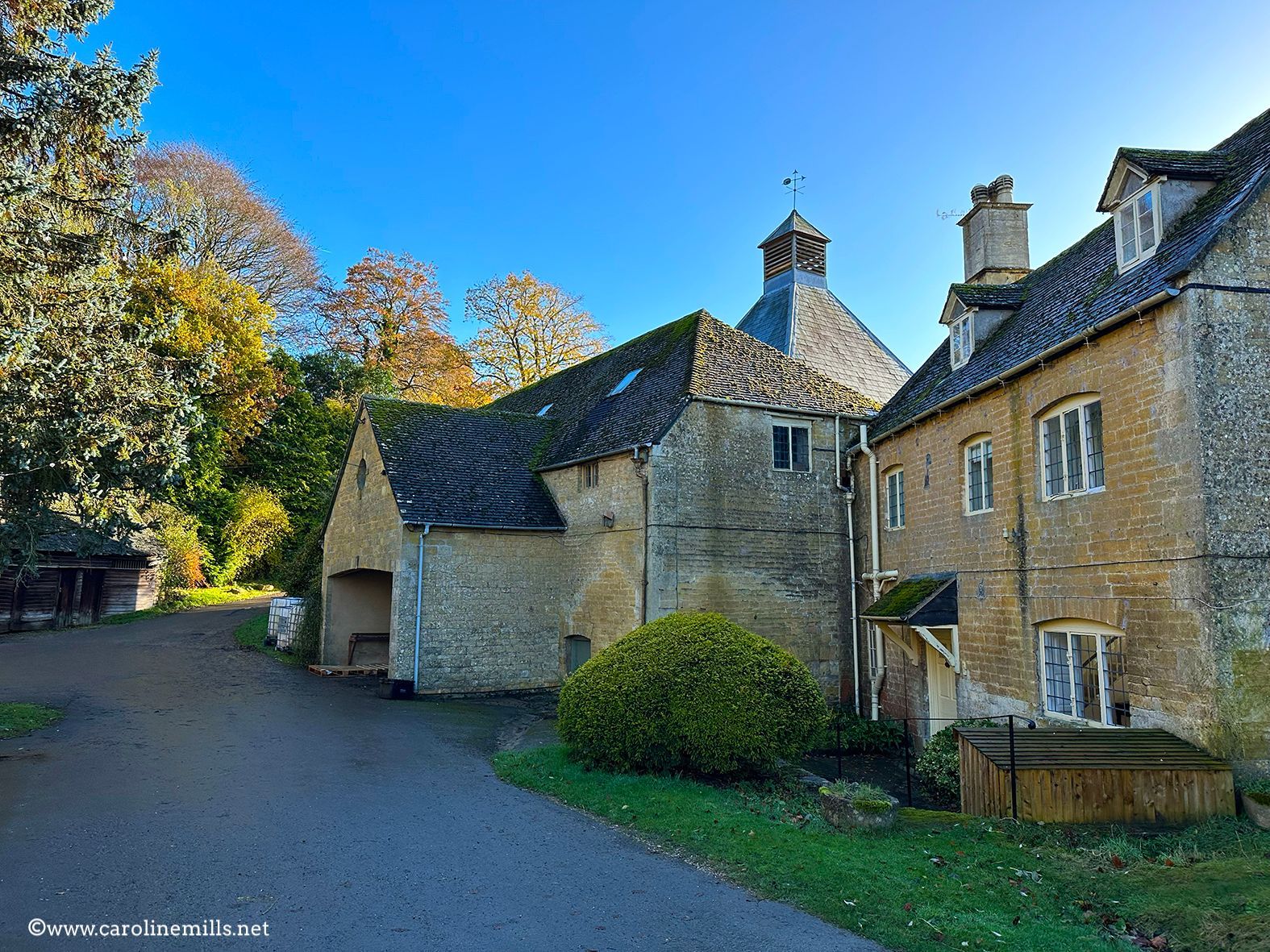 A large stone building in the Cotswolds with a blue sky in the background