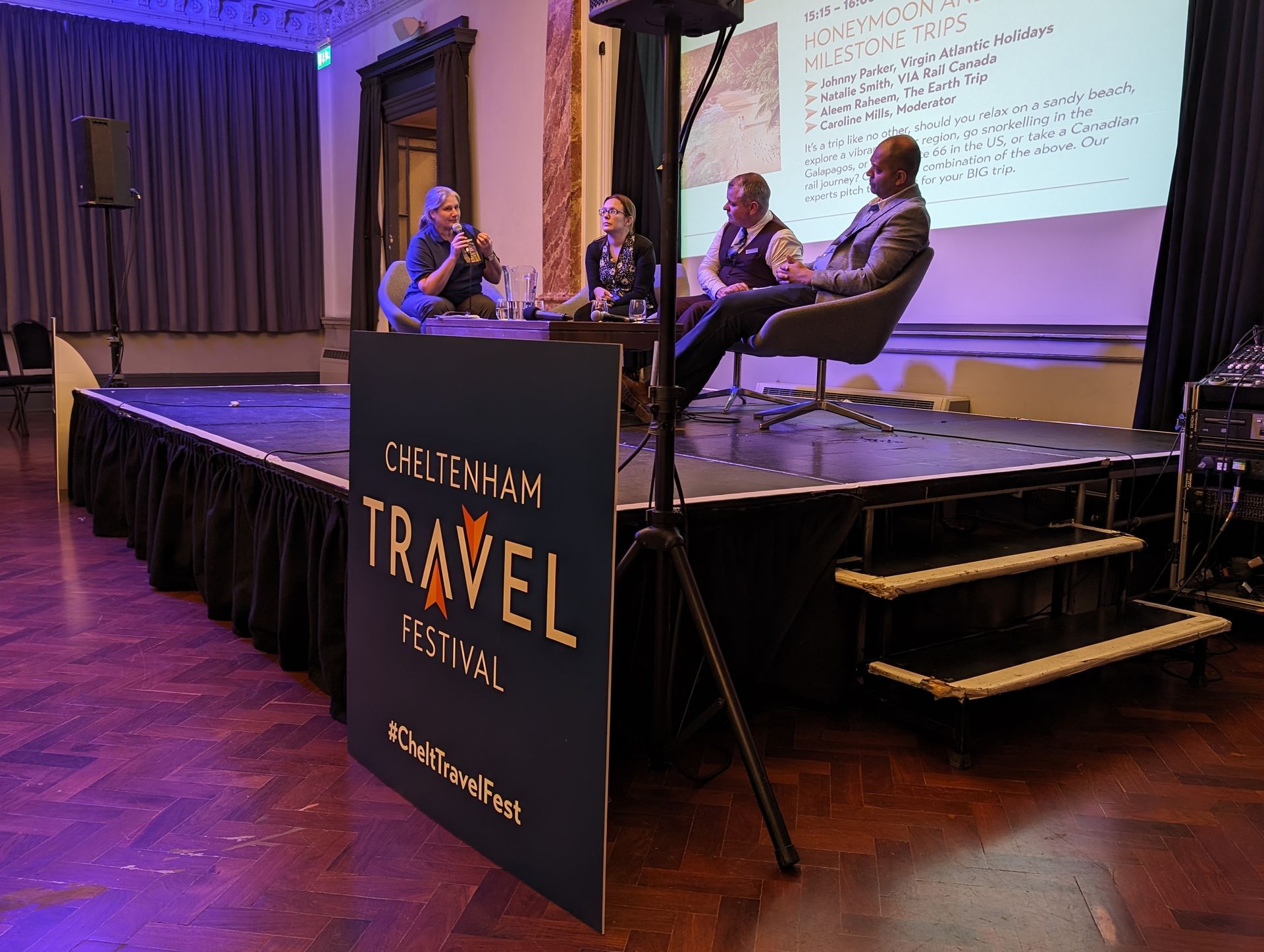 People sitting on a stage with a sign that says travel