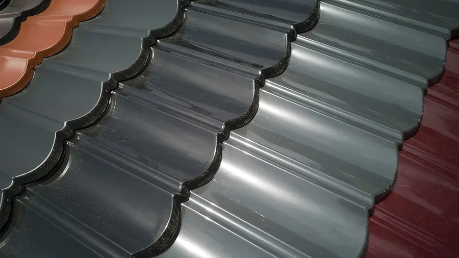 Close-up of glossy gray metal roofing tiles with scalloped edges on a red roof surface