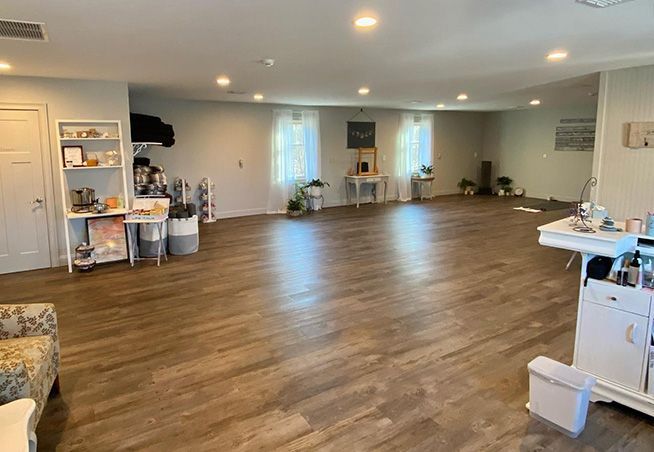 Spacious empty studio with wood floors, white walls, mirrors, and a small refreshment table on the right