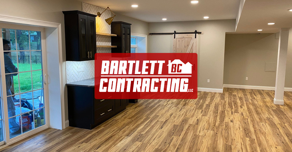 Modern open-concept room with wood floors, recessed lights, and a Bartlett Contracting logo overlay