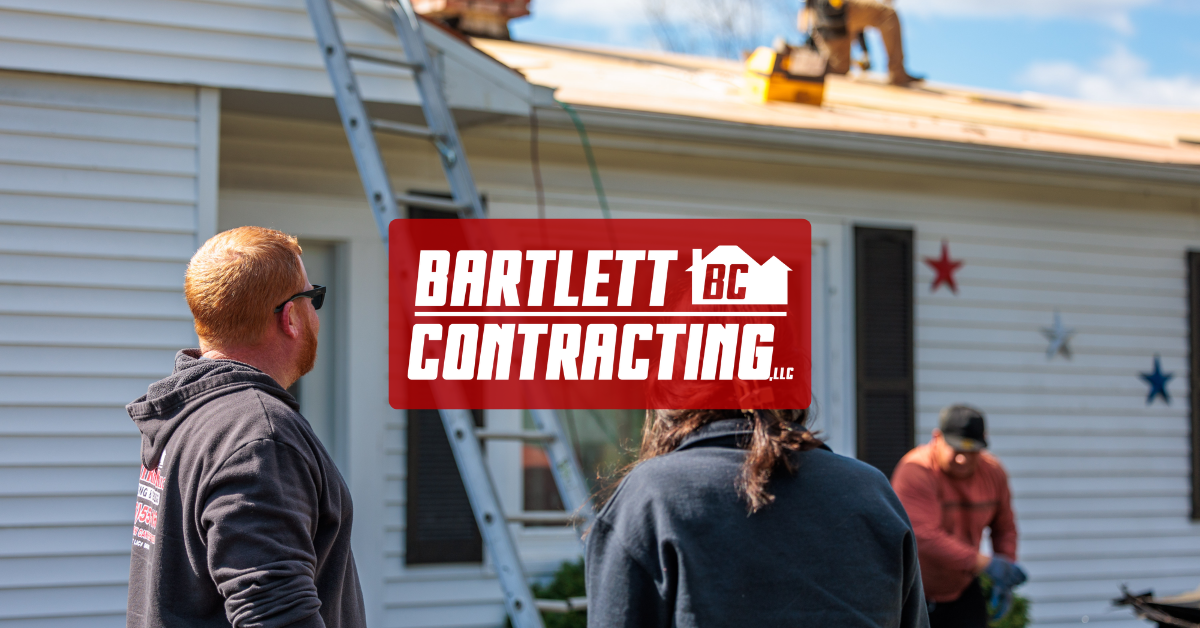 Three people view a house exterior with a red BARTLETT CONTRACTING sign hanging on it.