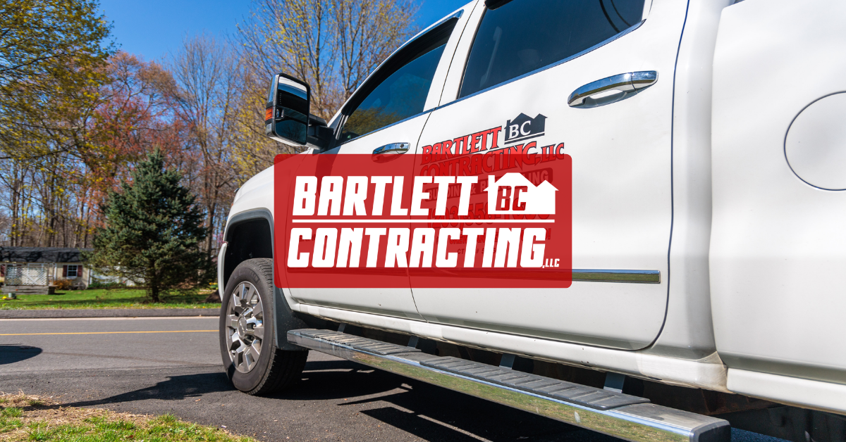 White Bartlett Contracting truck parked outdoors on a sunny street, with red company logo on the side.
