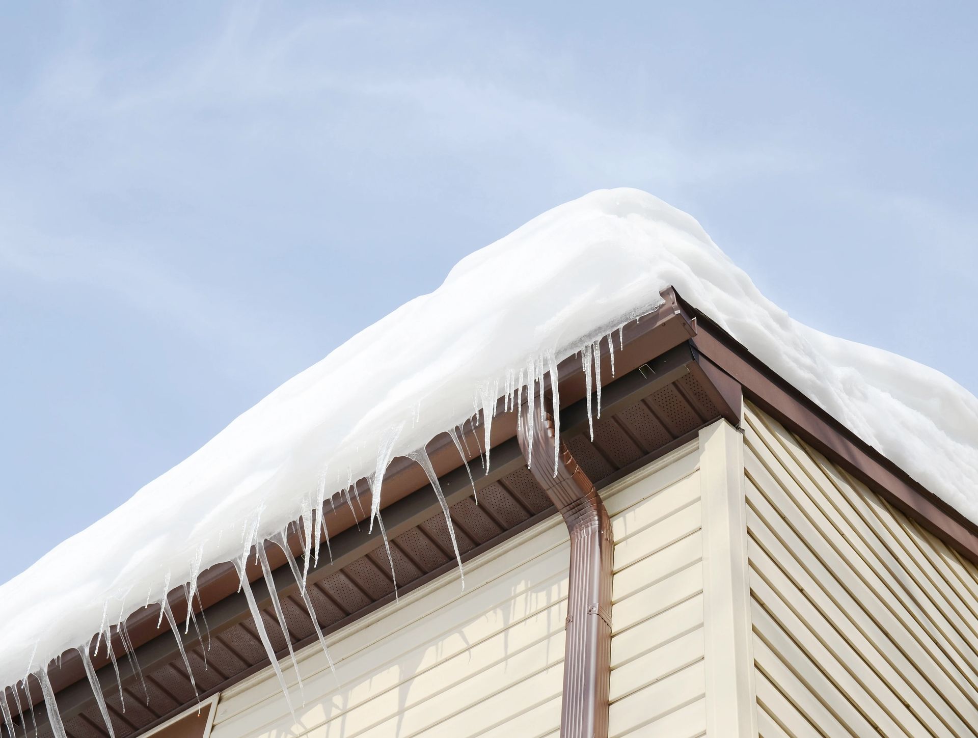 Snow-covered house roof with icicles hanging from the eaves