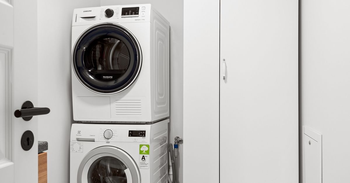 Laundry area with washer, dryer, and white cabinetry next to a kitchen