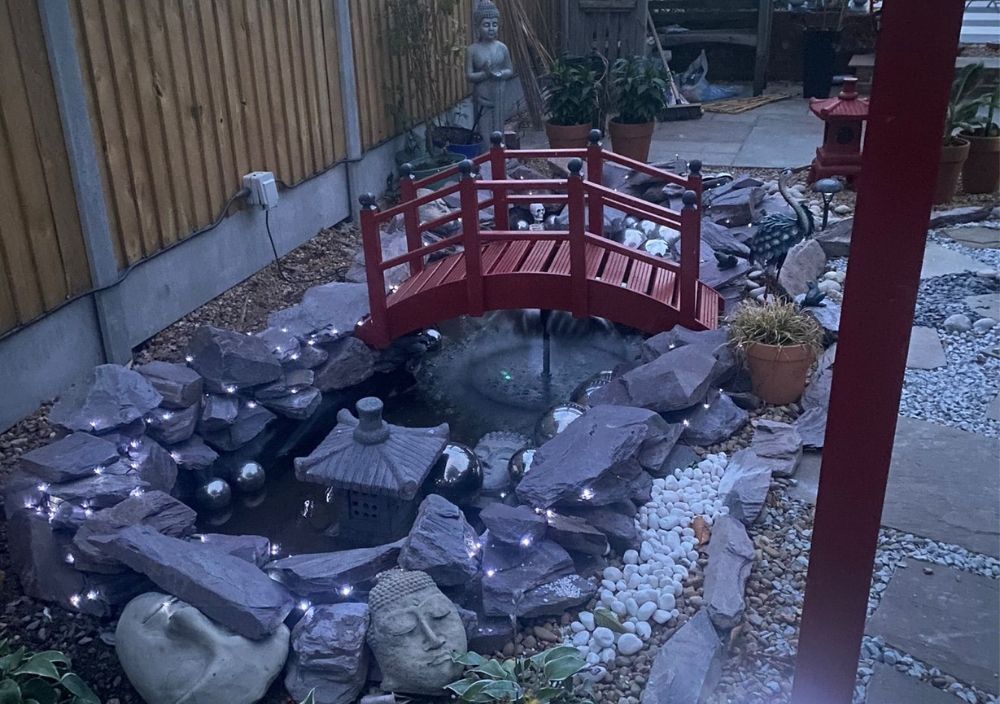 Pond and red bridge lit at dusk in a Japanese-style garden in Bramhope