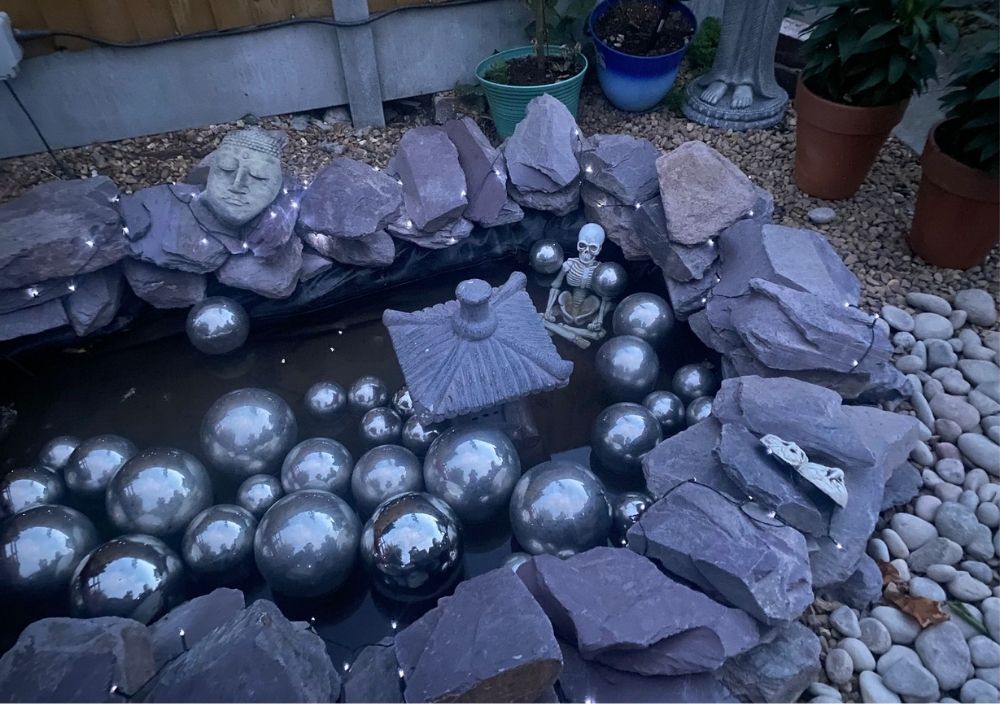 Small pond ringed with slate and filled with steel spheres in a Bramhope garden