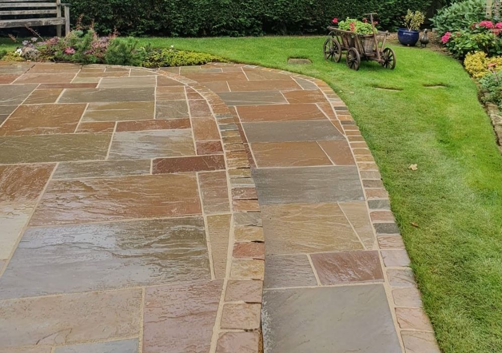 Large stepped Indian stone patio with a curved path laid by Paving Leeds in Alwoodley
