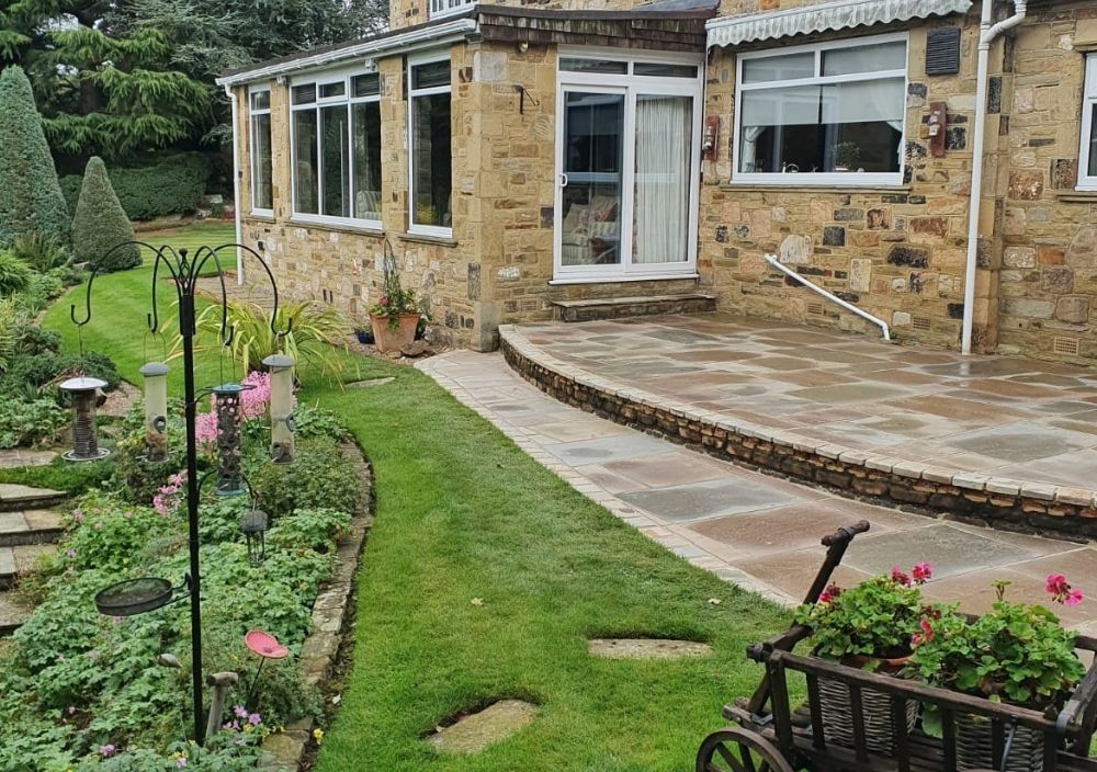 Two-level Indian stone patio with a curved step outside a house in Alwoodley