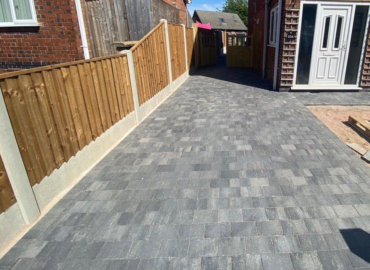 Grey block paving driveway beside a timber fence in Leeds