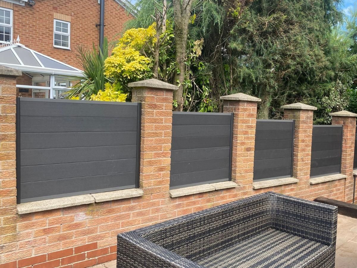 Smooth-faced anthracite grey composite fence panels fitted between brick pillars in Leeds