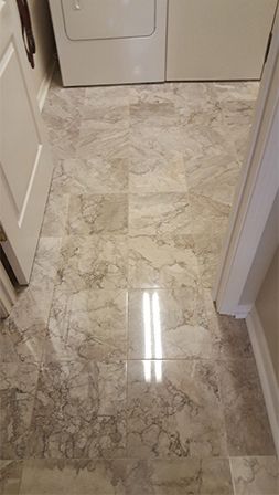 A laundry room with a marble floor and a washer and dryer.