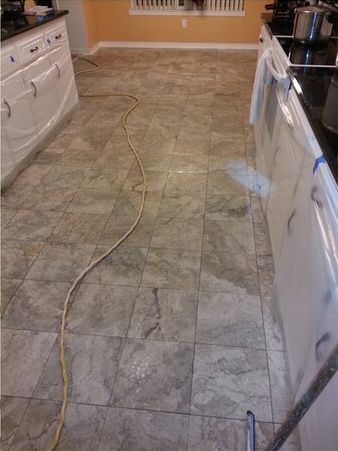 A kitchen with a tiled floor and a mop on the floor.