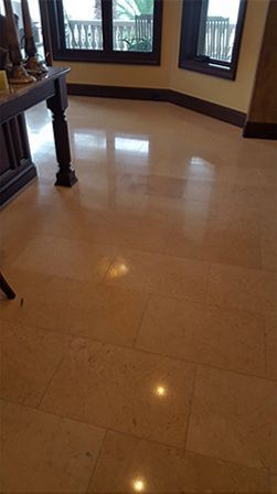 A marble floor in a living room with a table and windows.