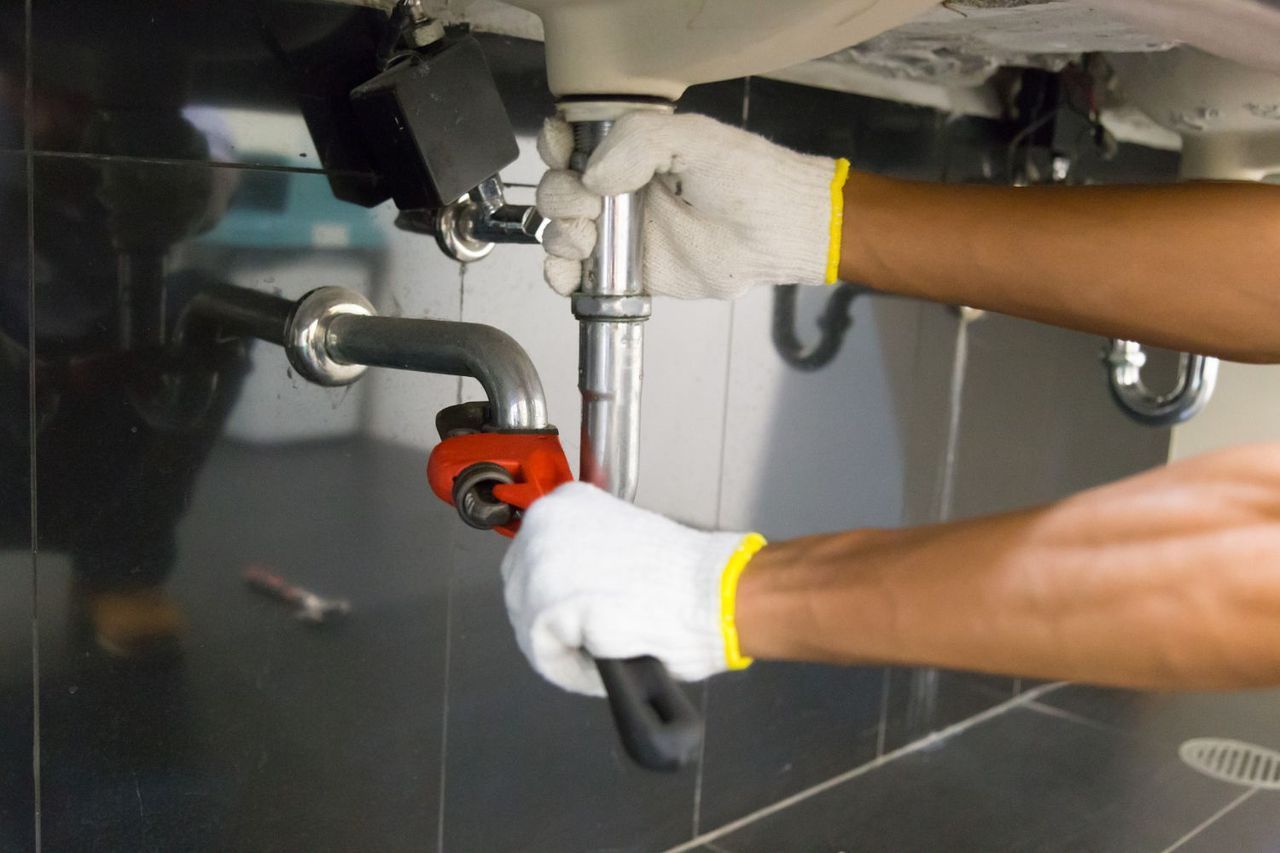 Man Working on a Pipe Under a Sink