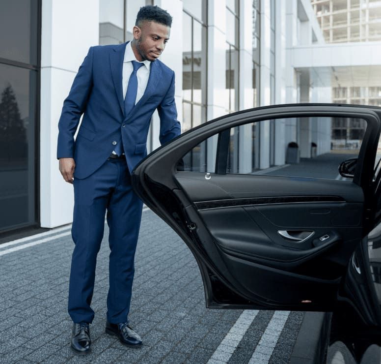 Professional chauffeur assisting VIP client with vehicle entry
