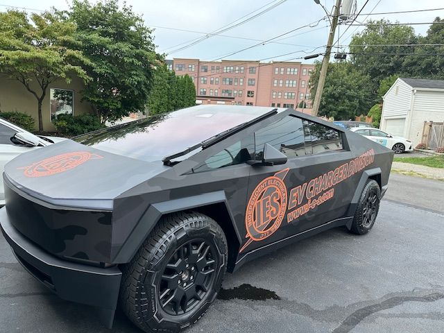 A black tesla cybertruck is parked on the side of the road. A black tesla cybertruck is parked on the side of the road.