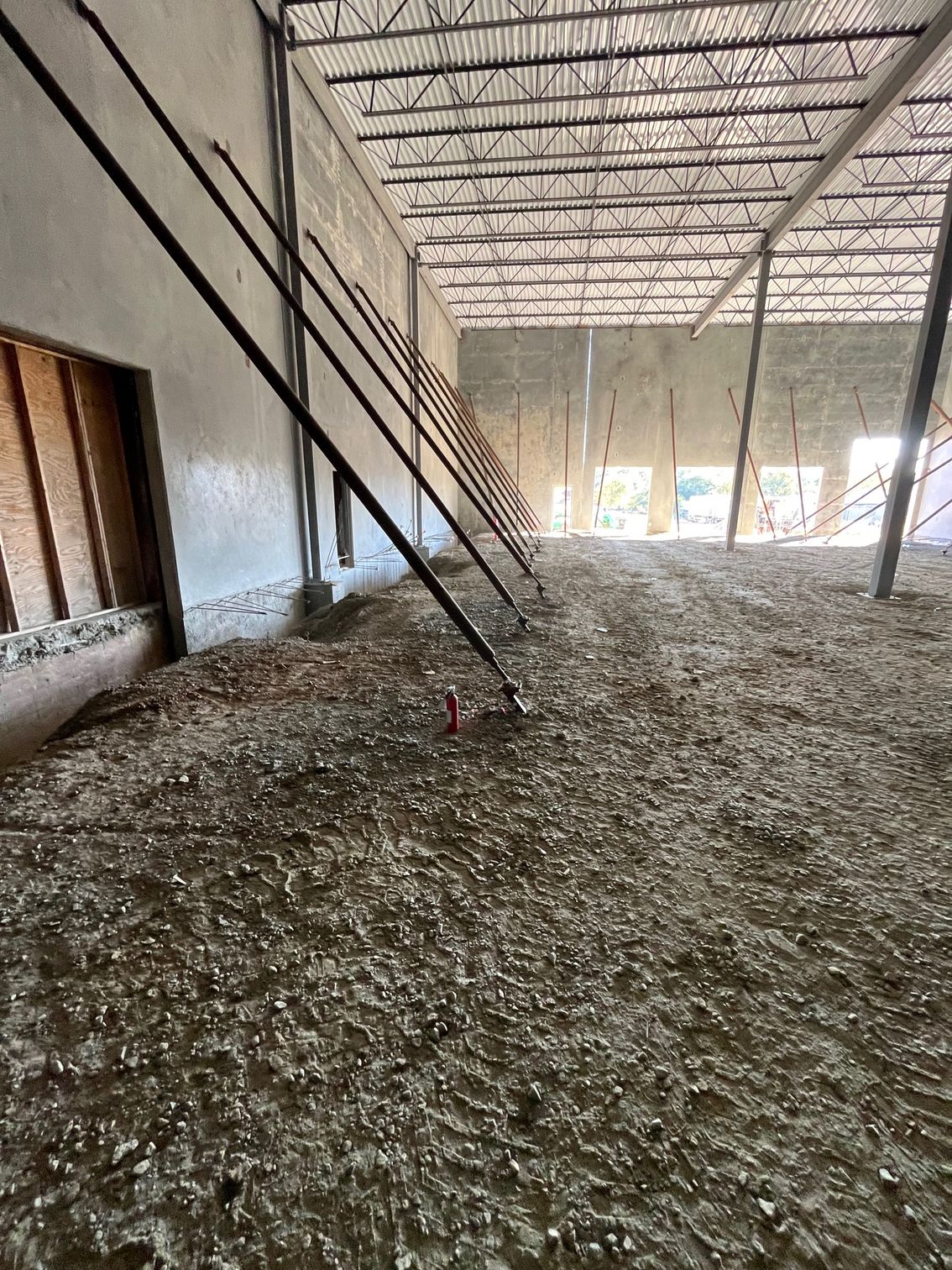 Interior of a building under construction, with a gravel-covered floor and exposed ceiling beams.