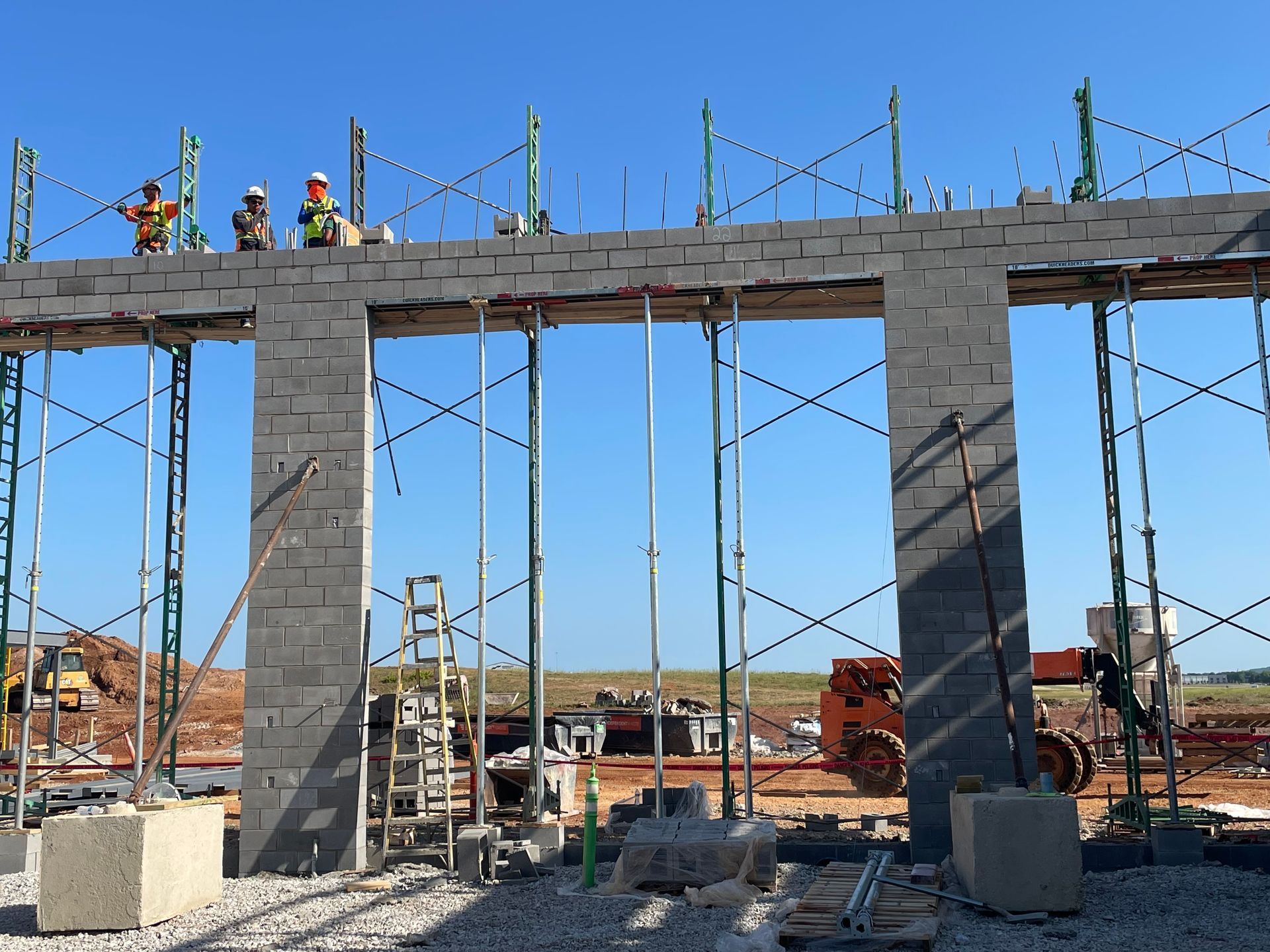 Construction workers atop a concrete bridge under construction against a clear blue sky