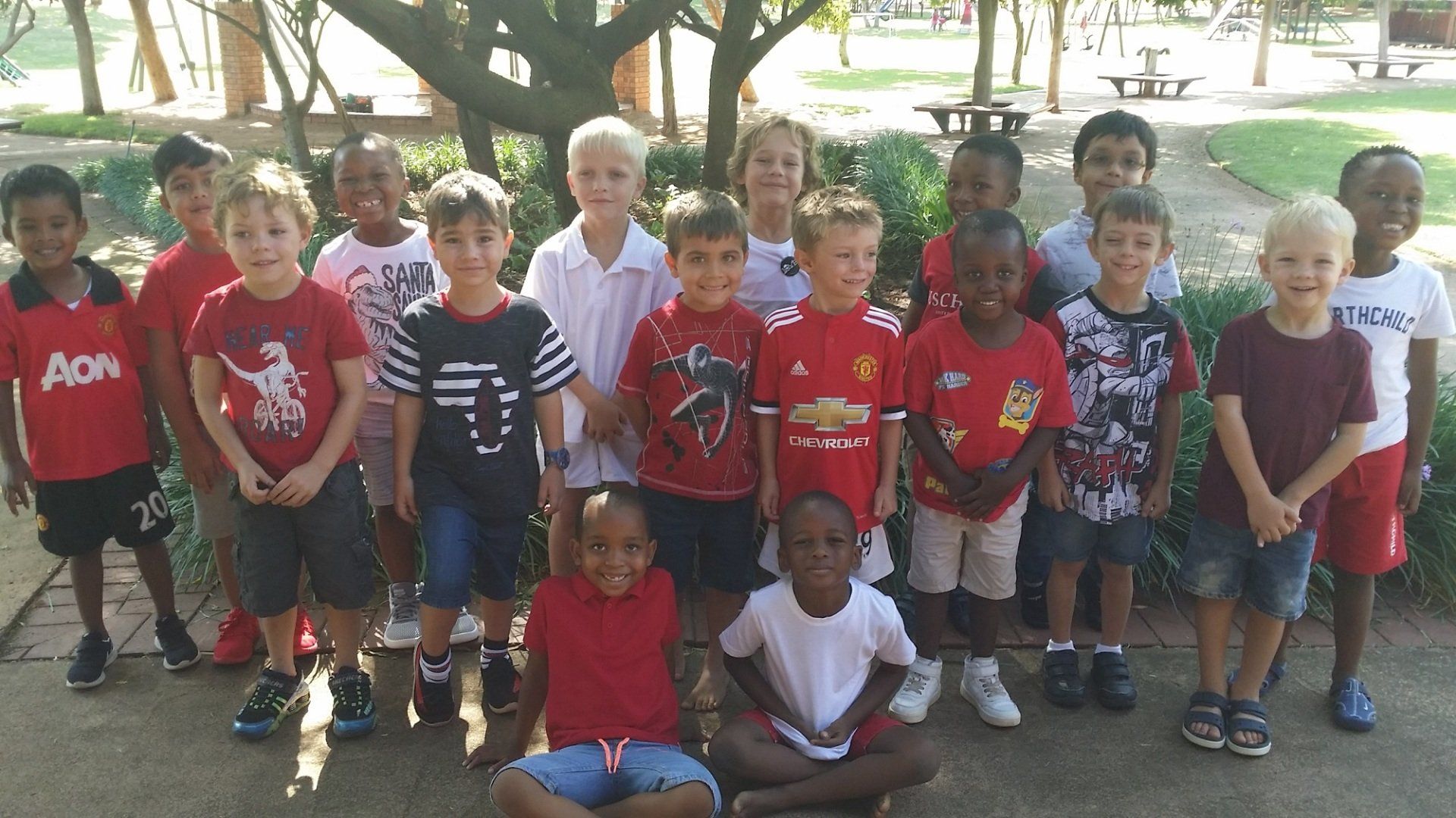 A group of young boys posing for a picture with one wearing an aon shirt