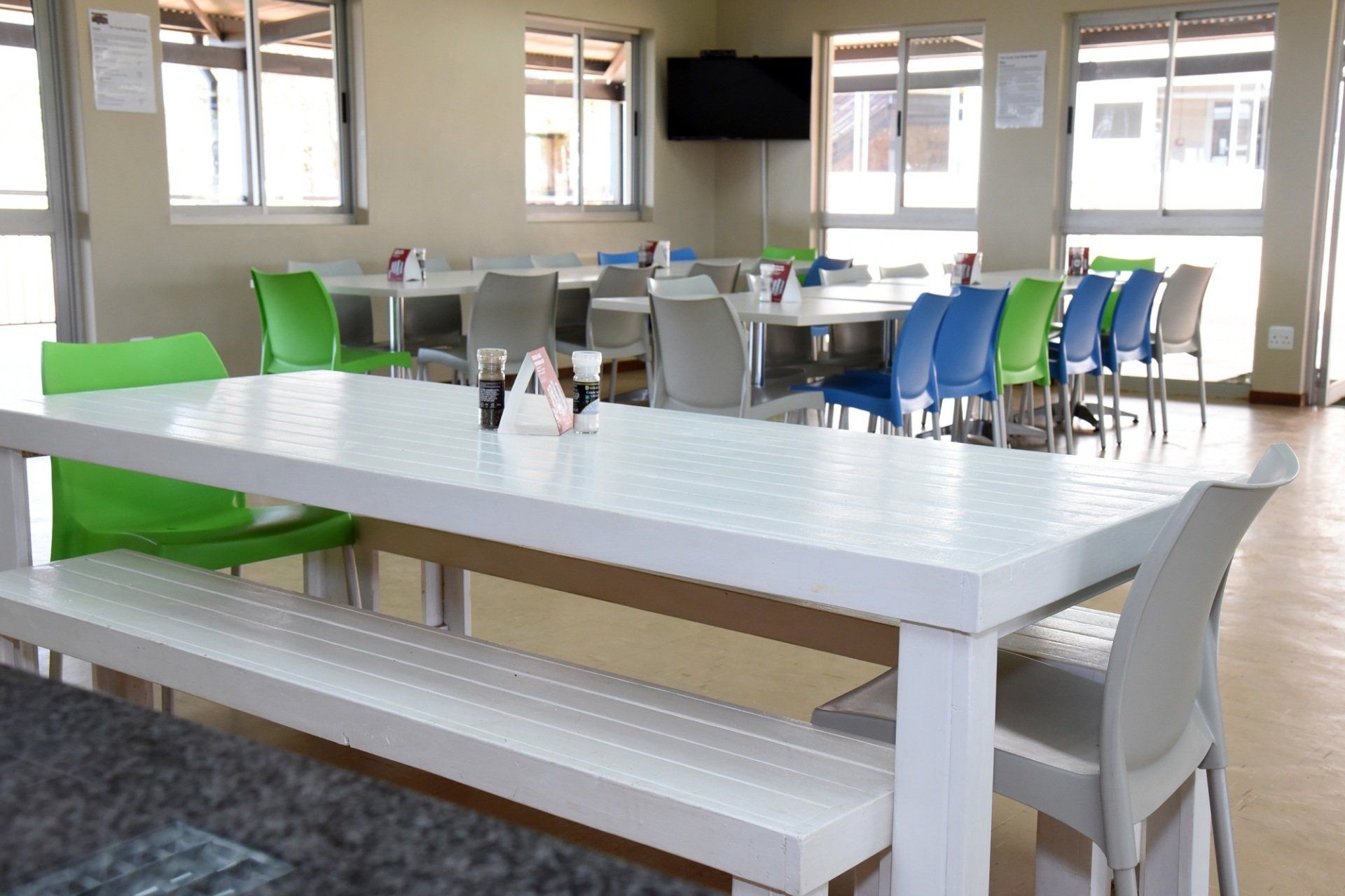 A dining room with white tables and green chairs