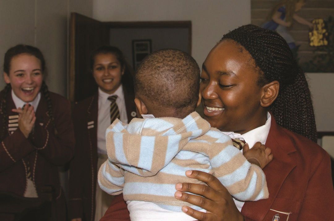 A woman is holding a baby in her arms and smiling