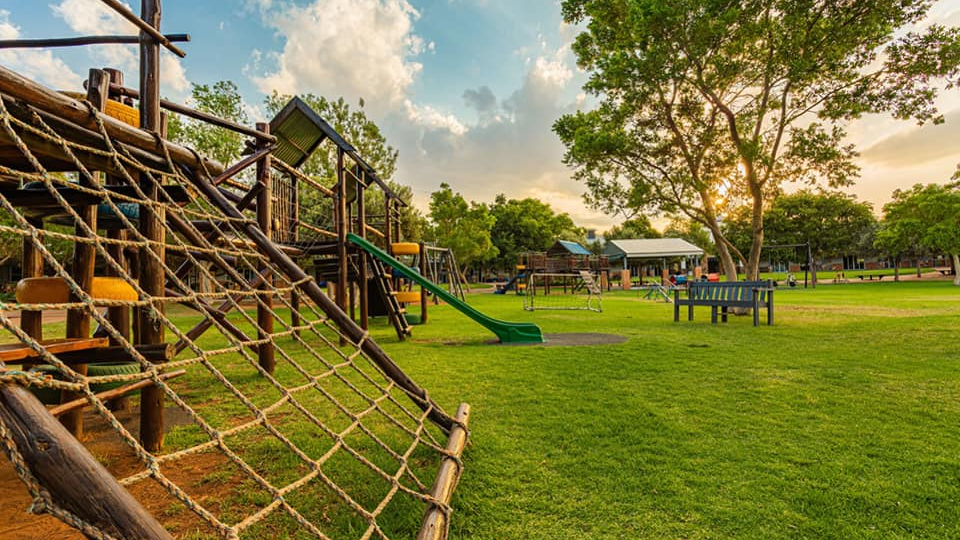 A playground with a slide and a rope ladder in a park.