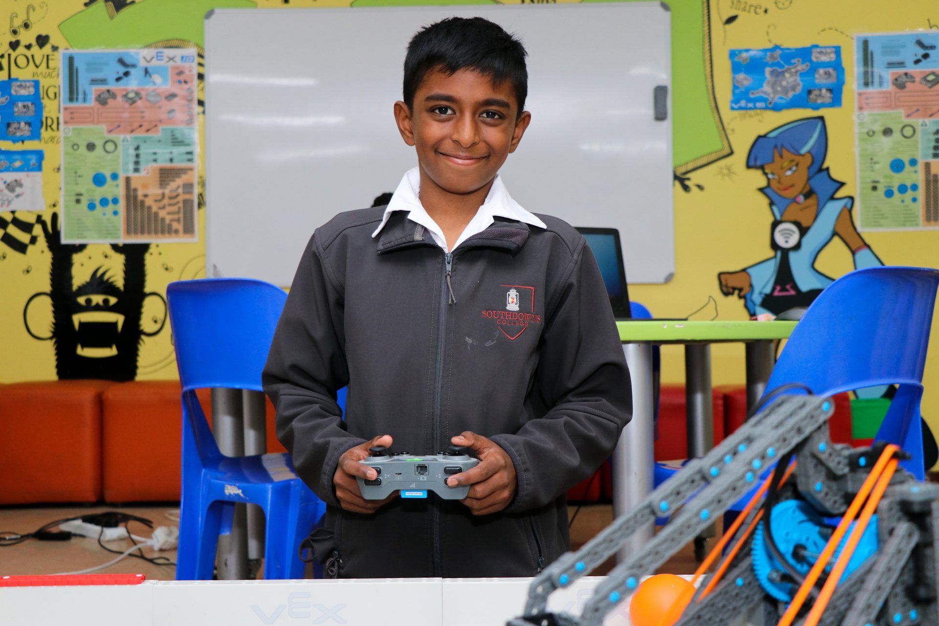 A young boy is holding a remote control in a classroom.