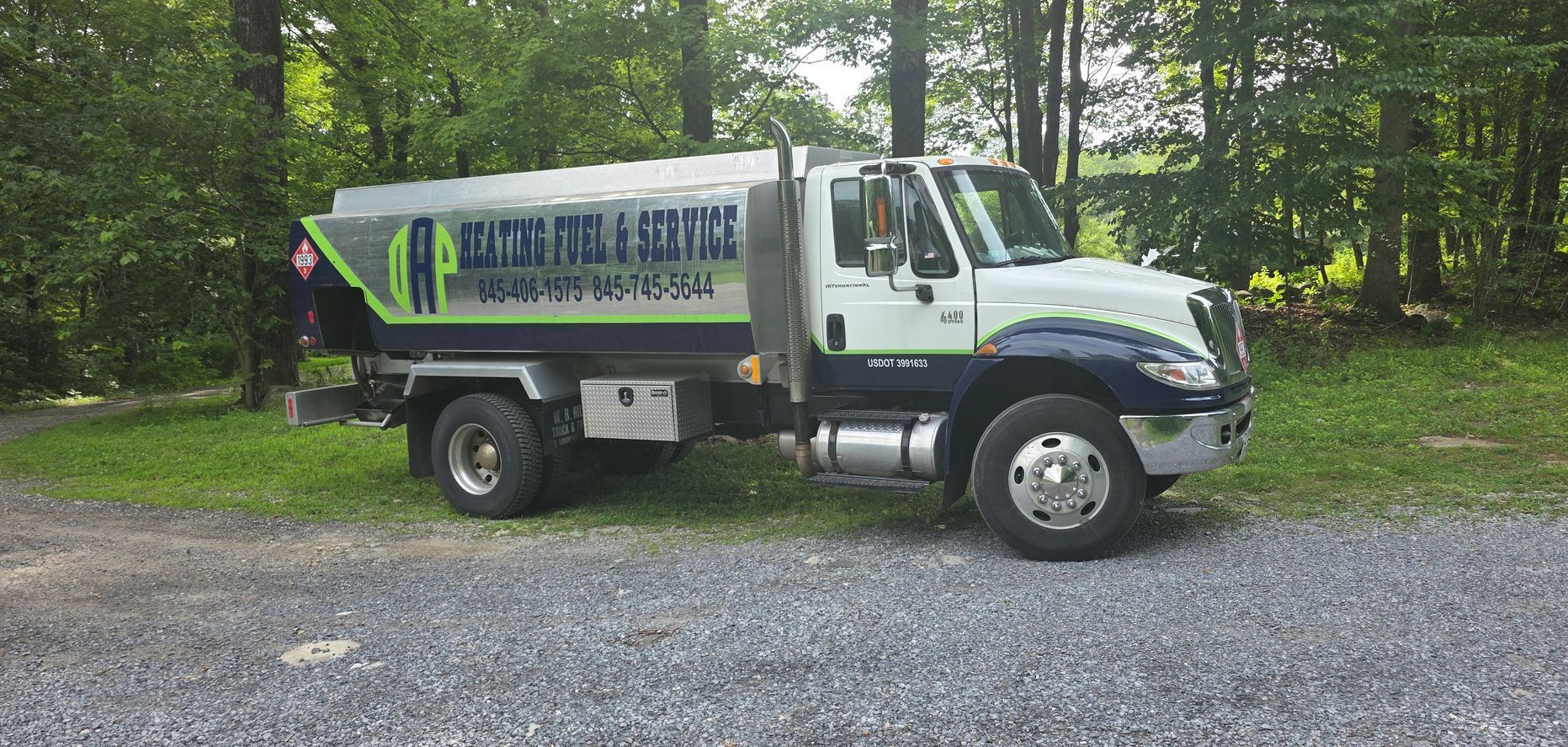 A tanker truck is parked in a gravel lot.
