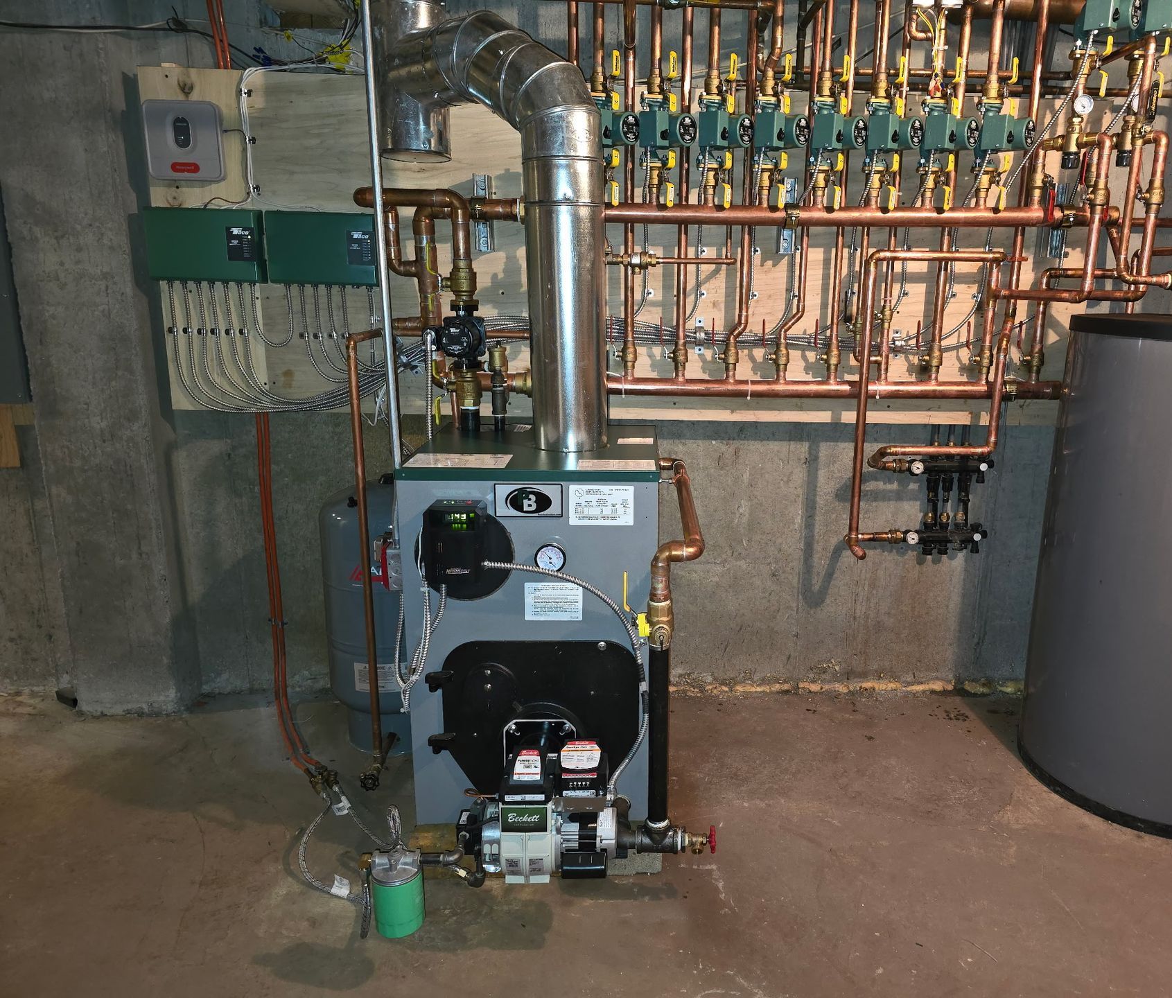 A boiler in a basement with copper pipes