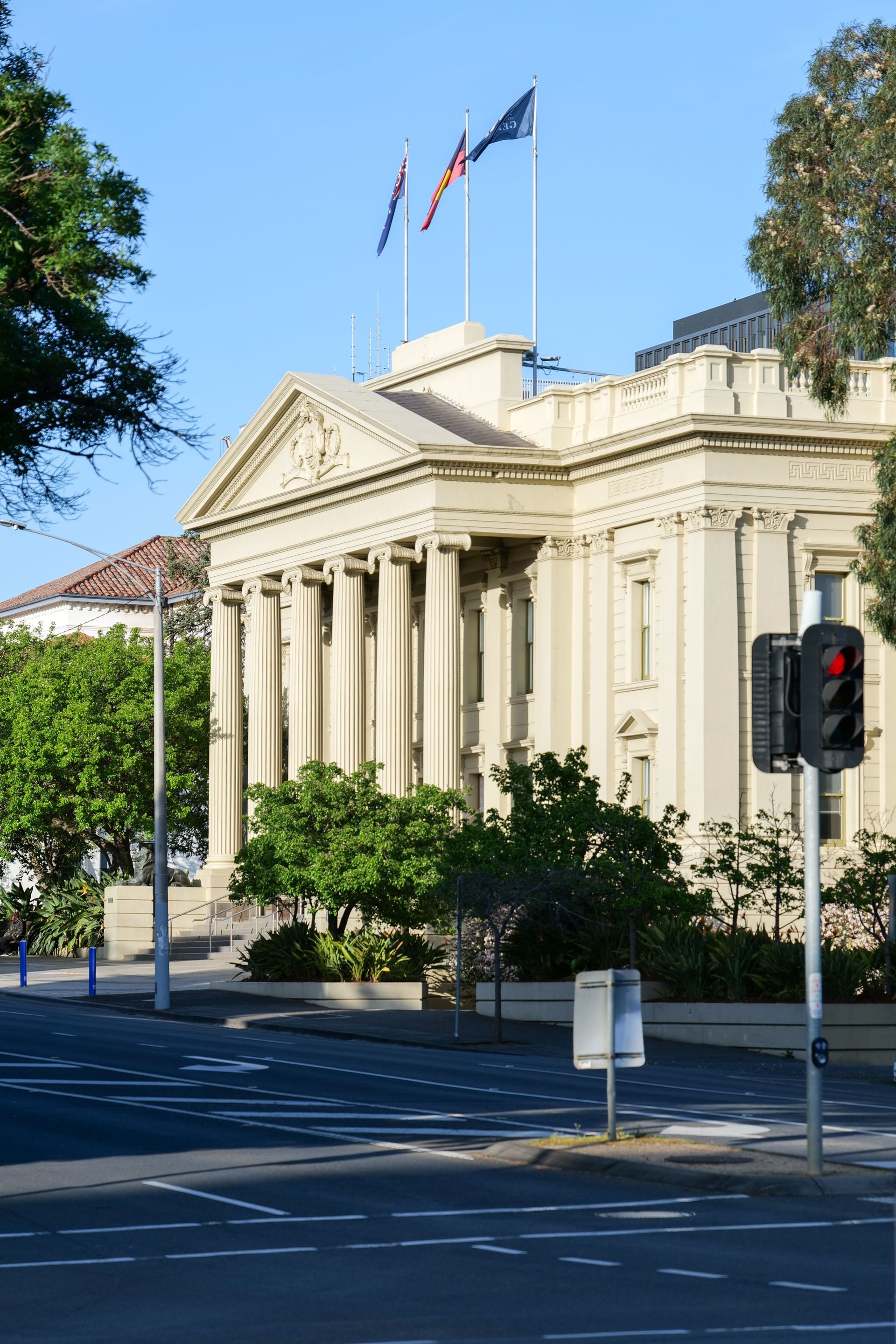 Historic beige civic building with columns and flags on a sunny street corner