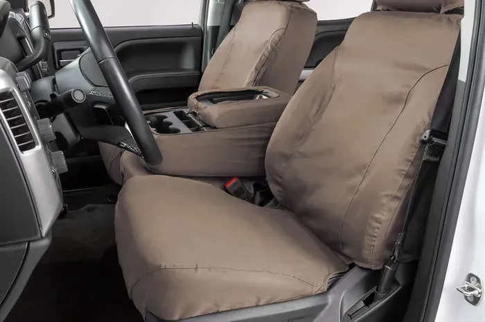 The front seats of a white truck with brown seat covers.