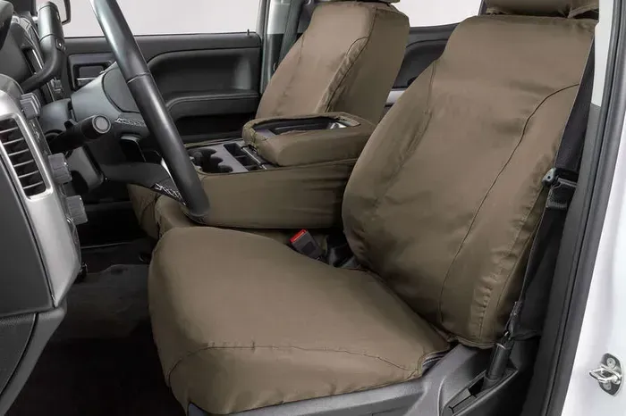 The front seats of a white truck with brown seat covers.