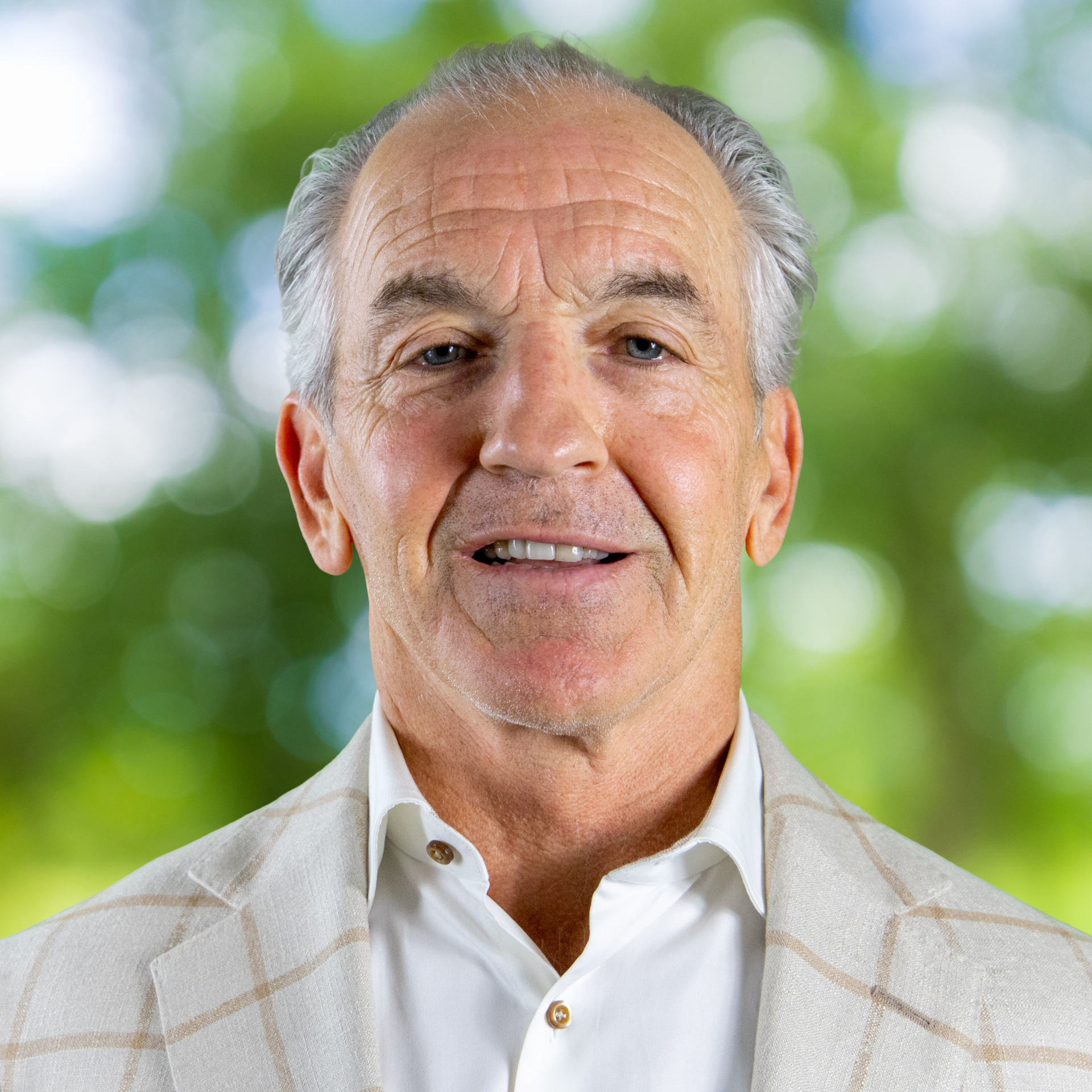 A person with light-colored hair wearing a light blue polo shirt, captured in a head-and-shoulders portrait outdoors.