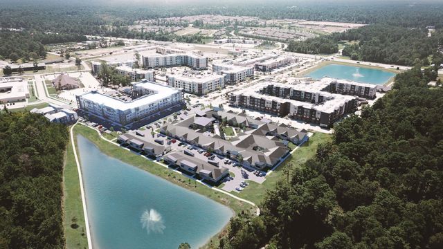 Aerial view of a residential apartment complex with multiple buildings, surrounding greenery, and two retention ponds.