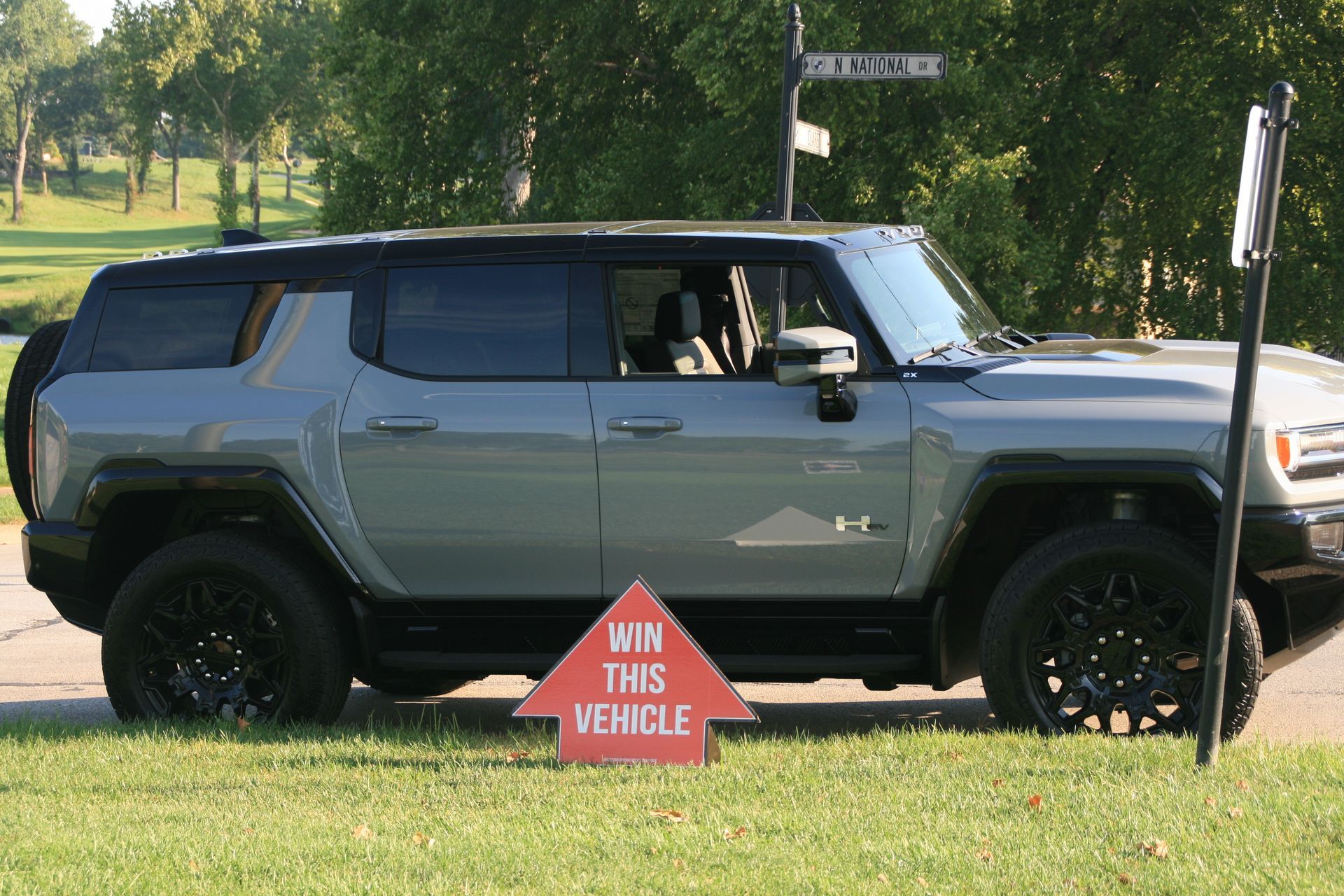 Gray Hummer EV with black accents, parked on grass next to a sign that reads “Win This Vehicle”.