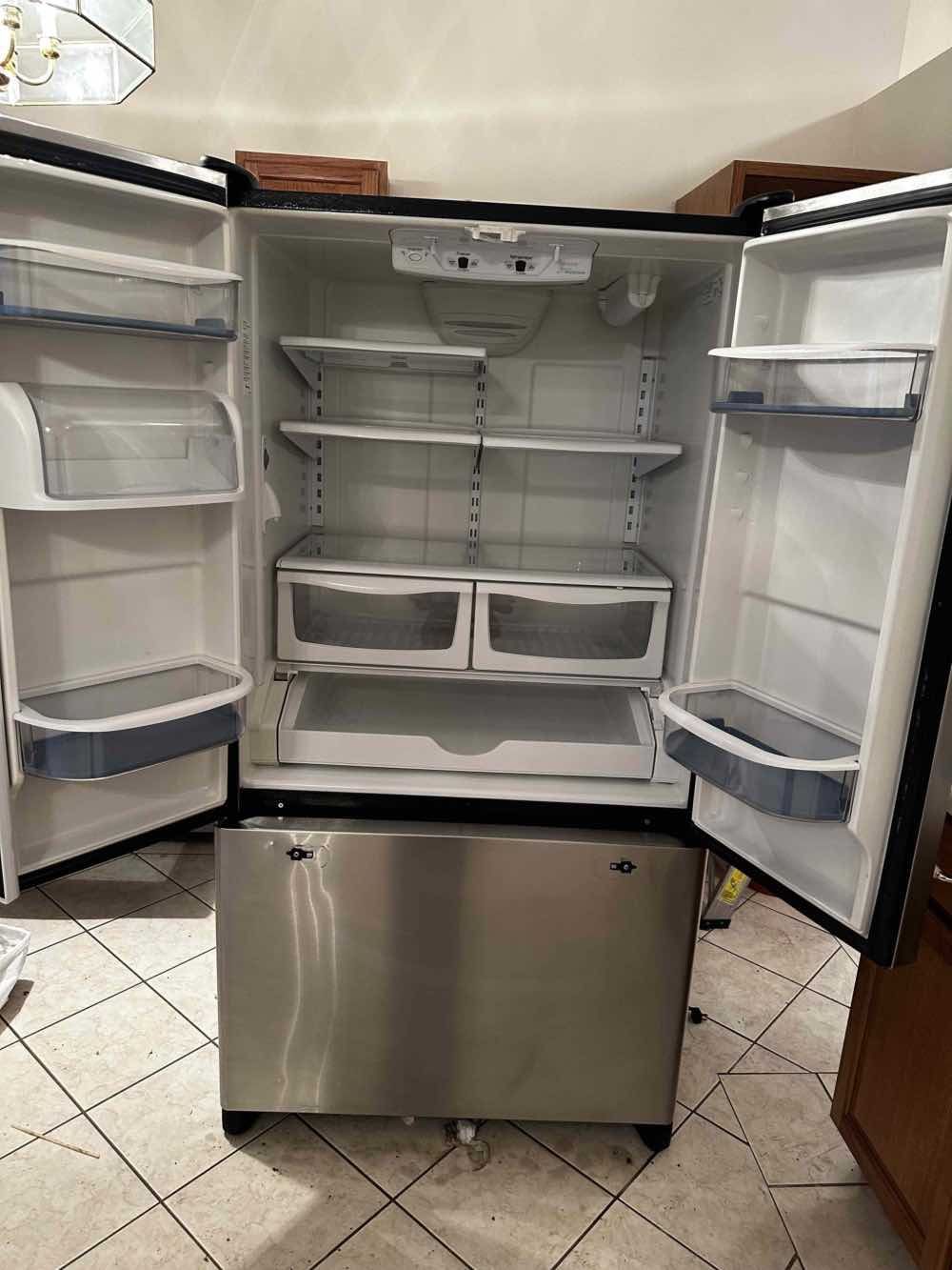 Stainless steel refrigerator with open doors, revealing shelves and drawers.