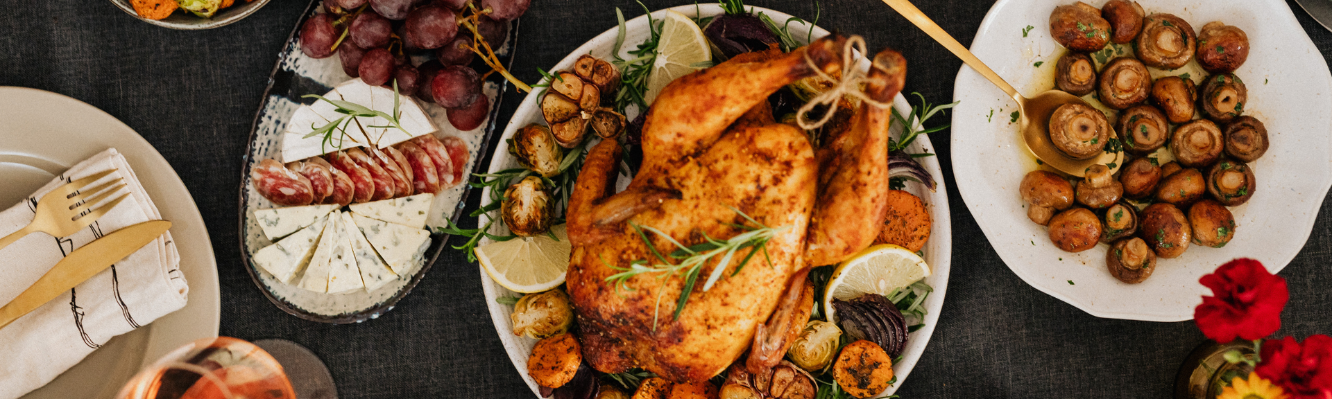 Overhead view of a roasted turkey dinner with side dishes, vegetables, and roasted potatoes on a table