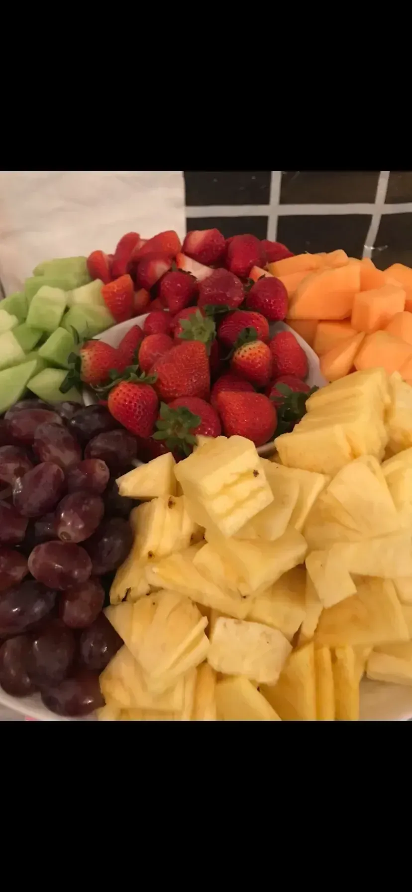 Assorted fresh fruit platter with strawberries, pineapple, grapes, melon, and cantaloupe cubes