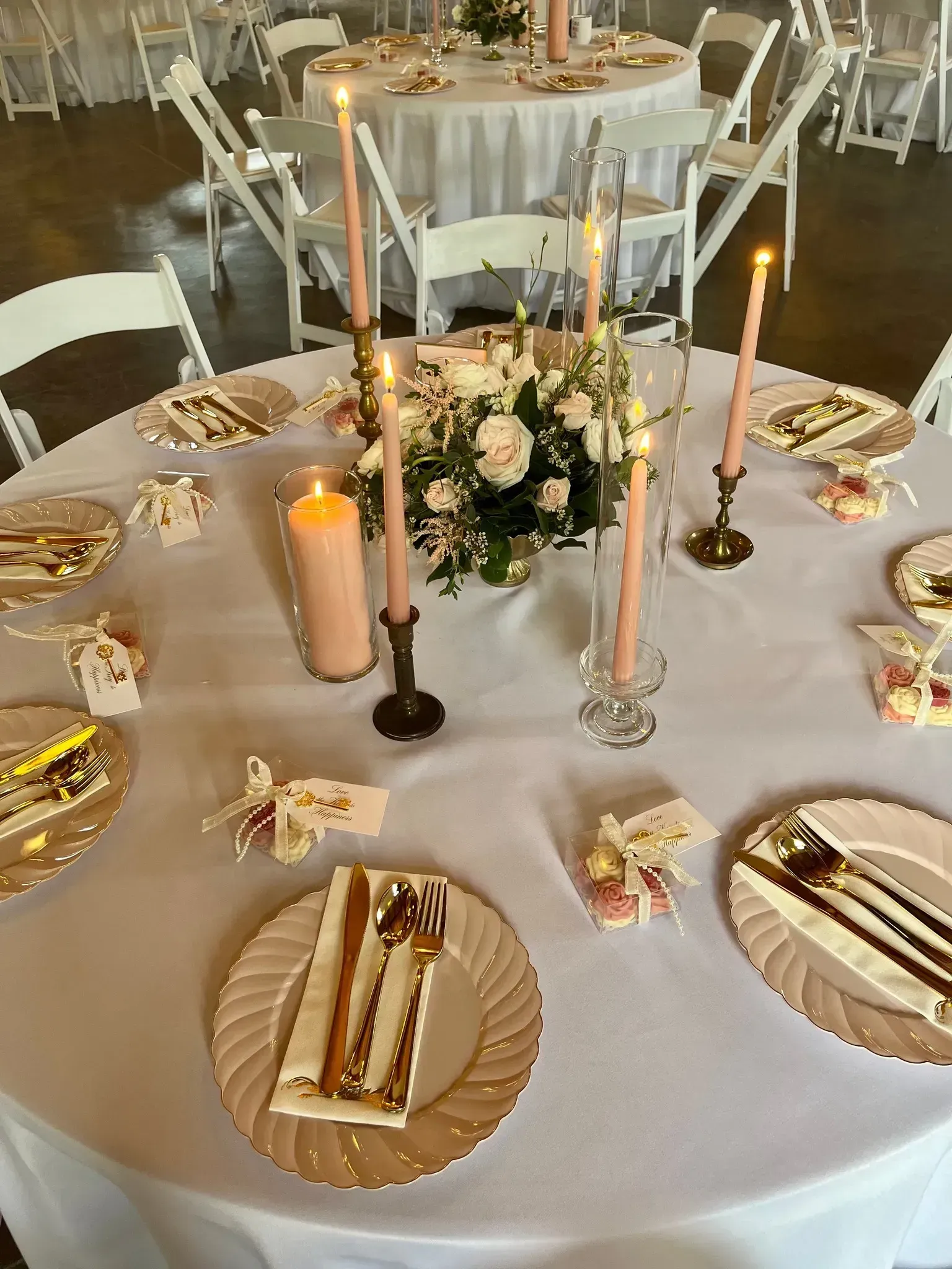 Elegant round banquet table with white linens, gold accents, candles, and a floral centerpiece