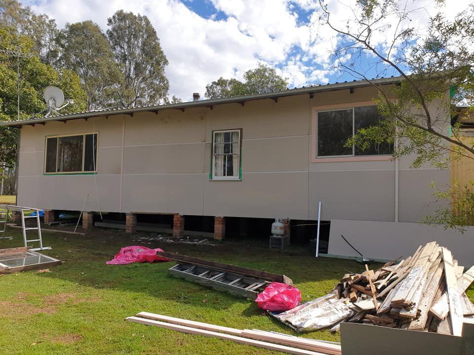 A House Is Being Remodeled In A Backyard With A Pile Of Wood — McCarthys Property Services in Grafton, NSW