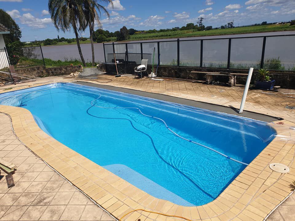 A Large Swimming Pool Is Surrounded By A Fence — McCarthys Property Services in Woolgoolga, NSW