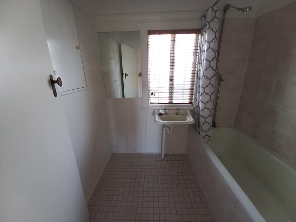 A Bathroom With A Sink, Bathtub, Window And Mirror — McCarthys Property Services in Yamba, NSW