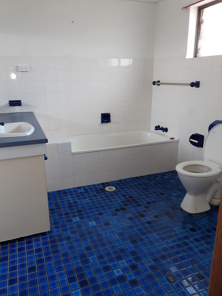 A Bathroom With Blue Tiles And A Toilet — McCarthys Property Services in Grafton, NSW