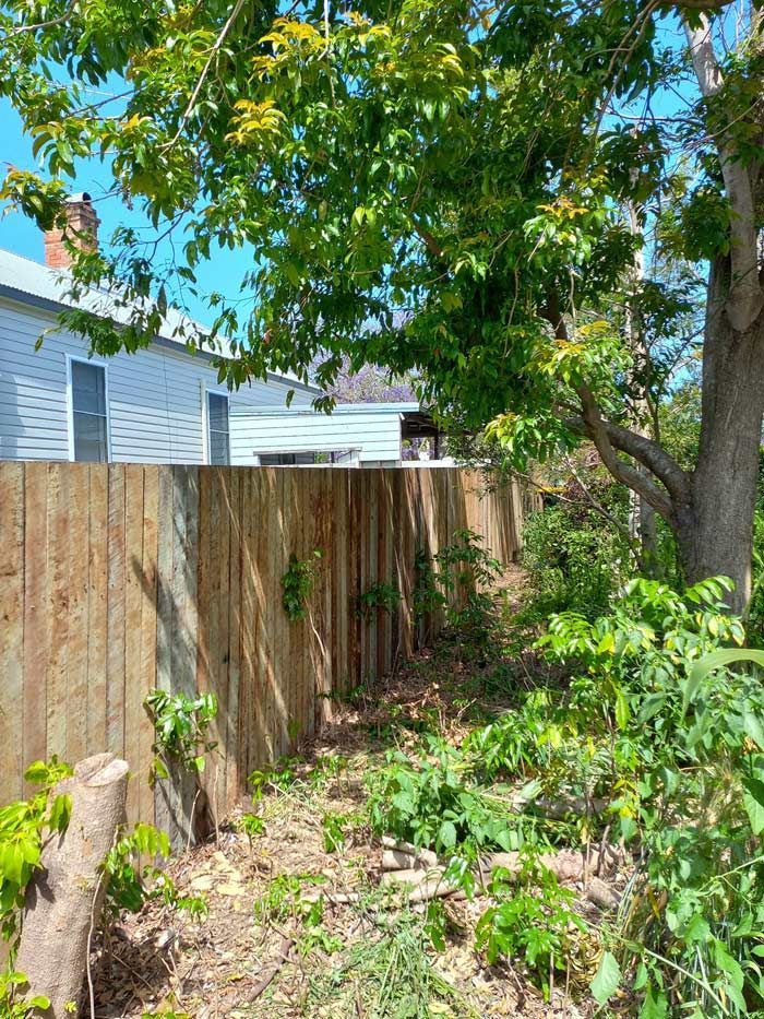 A Wooden Fence Is Surrounded By Trees — McCarthys Property Services in Maclean, NSW